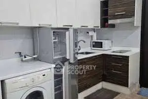 Modern kitchen with appliances including washing machine and microwave in compact layout.