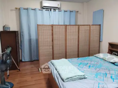 Cozy bedroom with wooden floor, air conditioning, and privacy screen