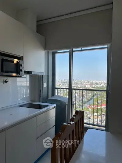 Modern kitchen with sleek cabinets and stunning city view from large window.