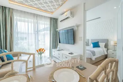Modern open-plan living room with dining area and bedroom view, featuring elegant decor and natural light.