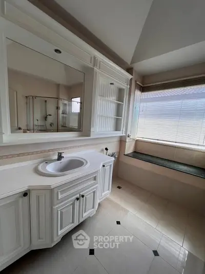 Spacious bathroom with elegant vanity and large window for natural light.