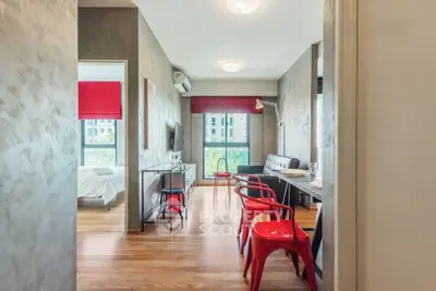 Modern apartment interior with open layout, featuring a stylish living area and bedroom with vibrant red accents.