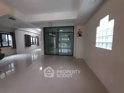 Spacious open-plan living area with large windows and modern glass partition.