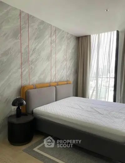 Modern bedroom with stylish decor and large window offering city views