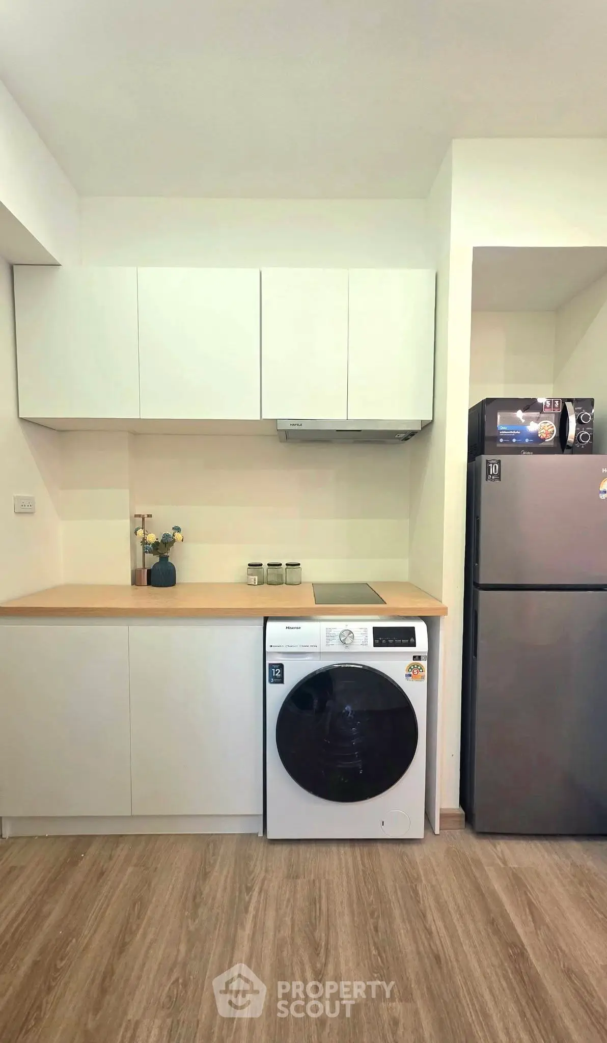 Modern kitchen with sleek cabinets, washing machine, and fridge in compact layout.
