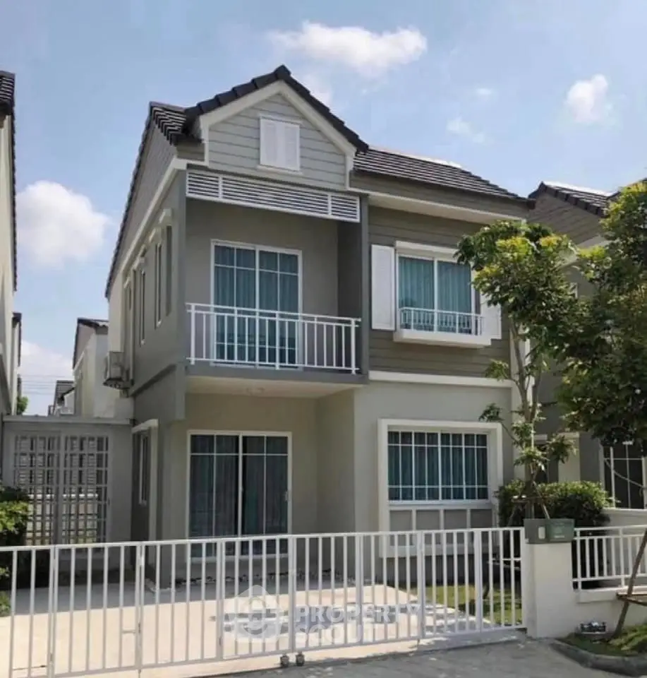 Charming two-story house with modern facade and gated entrance in a serene neighborhood.