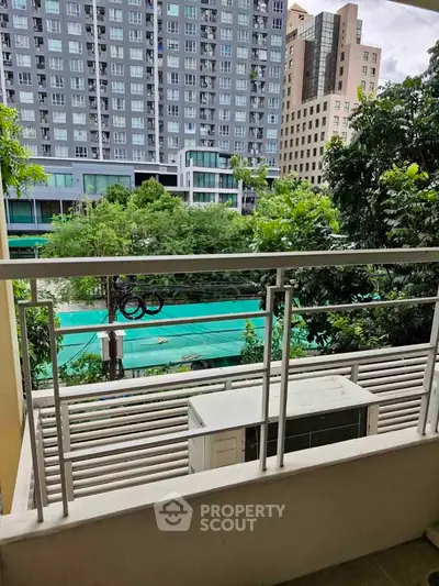 Charming balcony view overlooking lush greenery and modern cityscape, perfect for relaxation and urban living.