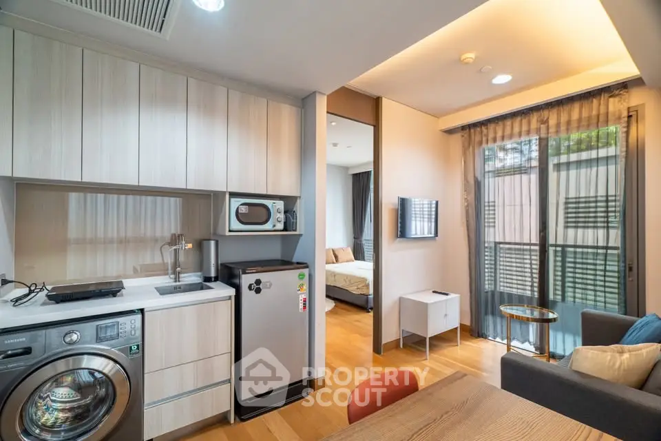 Modern apartment interior with open kitchen, cozy living area, and bedroom view, featuring sleek appliances.
