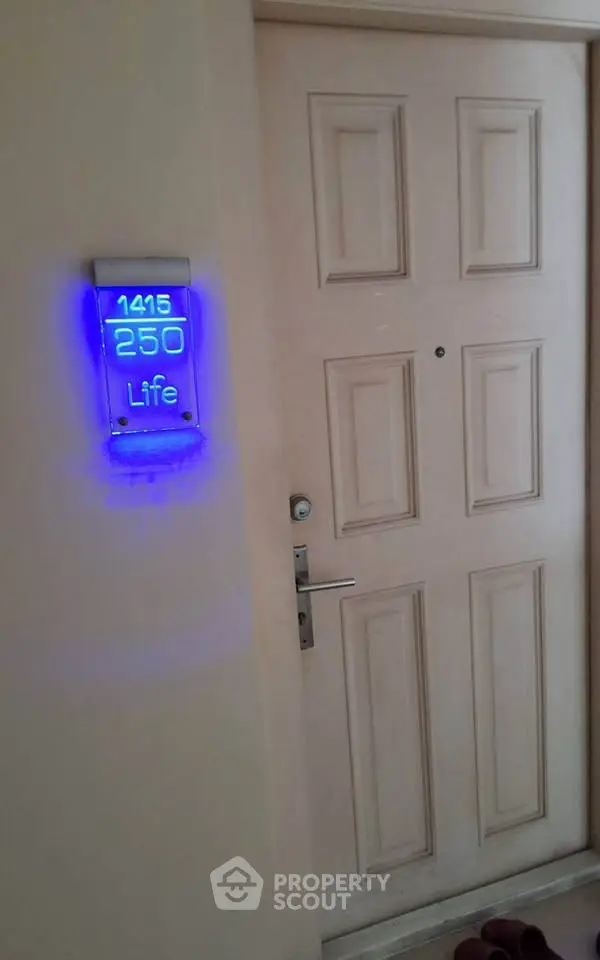 Modern apartment entrance with illuminated door number and sleek design.