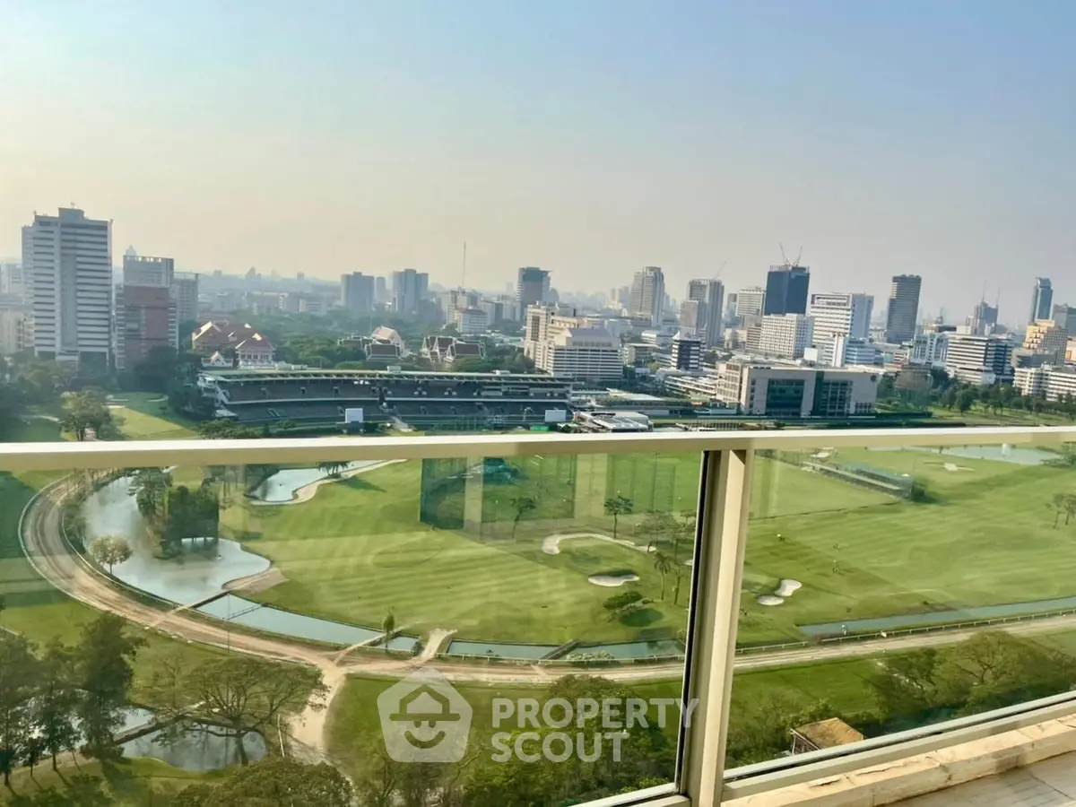 Stunning cityscape view from a high-rise balcony overlooking a lush golf course and skyline.