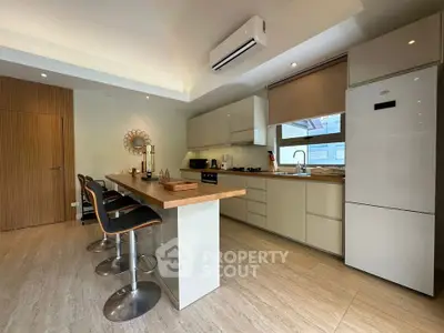 Modern kitchen with sleek cabinetry, island seating, and built-in appliances in a stylish home.