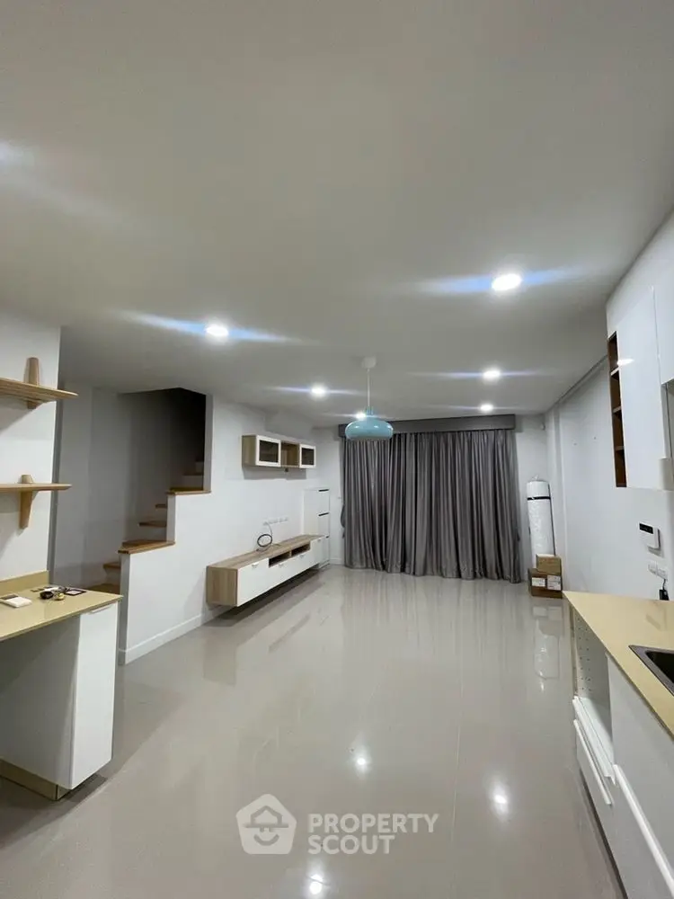 Modern open-plan living room with sleek kitchen and staircase