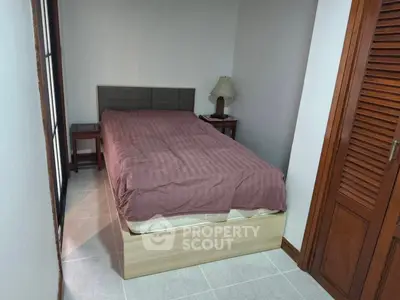Cozy bedroom with wooden furniture and natural light, perfect for relaxation.