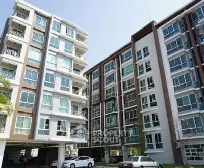 Modern apartment buildings with large windows and parking area, showcasing urban living.