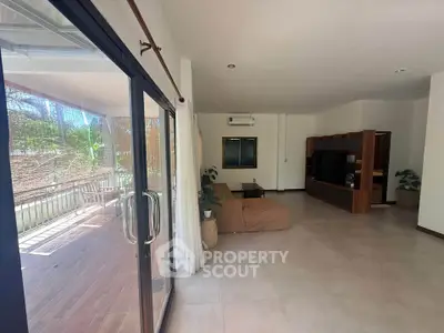 Spacious living room with large balcony access and modern entertainment center.