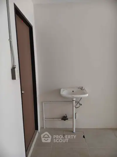 Minimalist utility area with sink and door, ideal for compact spaces.