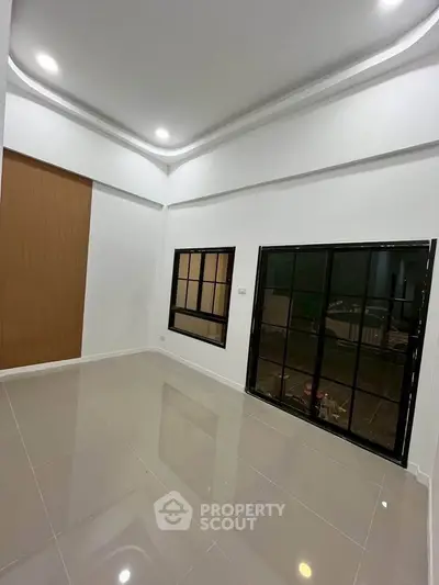 Spacious modern living room with sleek tile flooring and large windows for natural light.