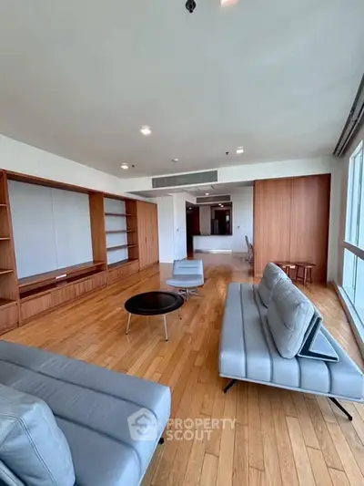 Spacious modern living room with sleek furniture and wooden flooring, offering a bright and inviting atmosphere.