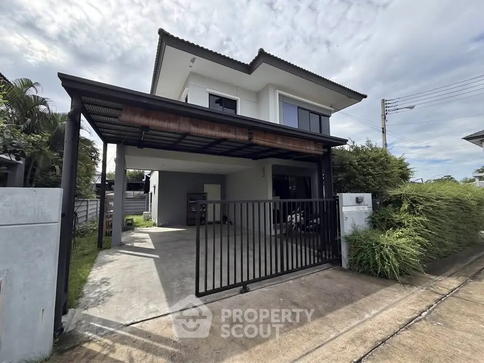 Modern two-story house with carport and gated driveway in a suburban neighborhood.