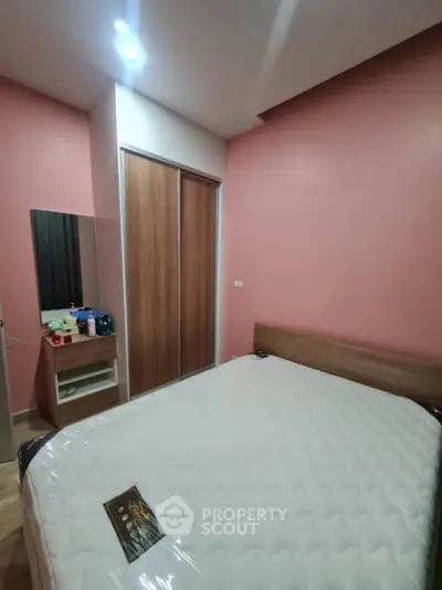 Cozy bedroom with pink walls and wooden wardrobe, perfect for relaxation.