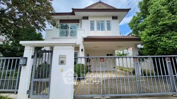 Charming two-story house with gated entrance and lush greenery, perfect for family living.