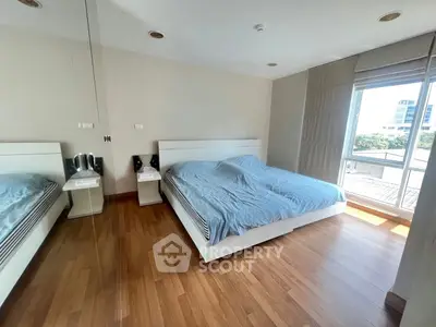 Spacious bedroom with large window and wooden flooring in modern apartment