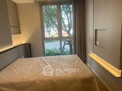 Cozy bedroom with large window and modern design, offering a serene view of greenery.