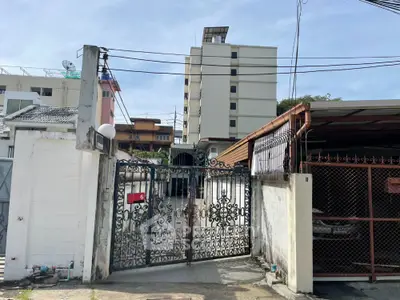 Charming gated entrance to urban residential property with adjacent covered parking area.