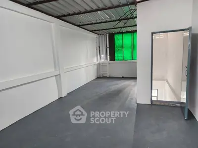 Spacious industrial-style room with metal roof and large window, ideal for creative workspace or storage.