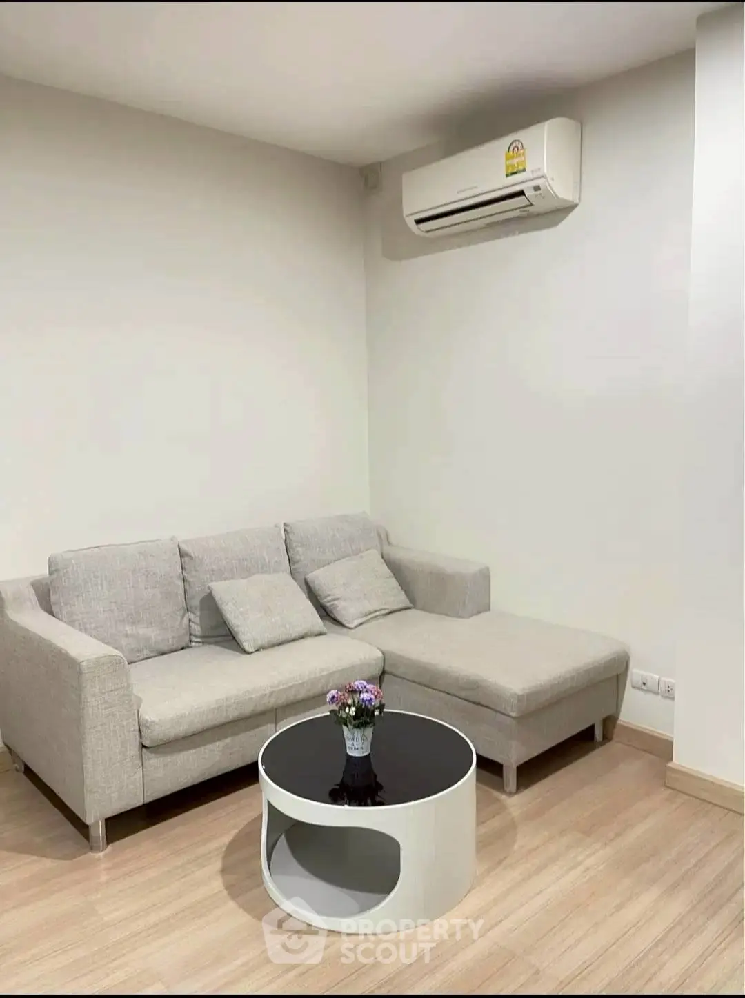 Modern living room with sleek gray sofa and stylish coffee table, featuring minimalist decor and air conditioning.