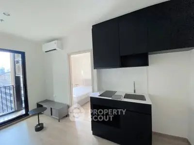 Modern apartment with sleek black kitchen and bright bedroom view