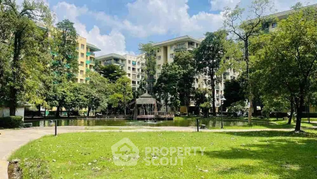Scenic view of residential buildings with lush green park and pond