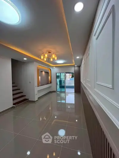 Modern interior with sleek lighting and glossy tiled floors, showcasing a stylish staircase and open layout.
