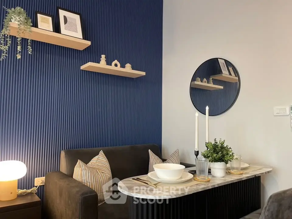 Stylish modern living room with blue accent wall, cozy sofa, and elegant dining setup.