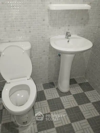 Modern bathroom with sleek pedestal sink and tiled walls, perfect for contemporary living.