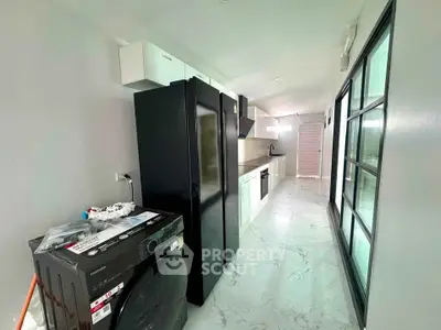 Modern kitchen with sleek black appliances and marble flooring in a stylish apartment.