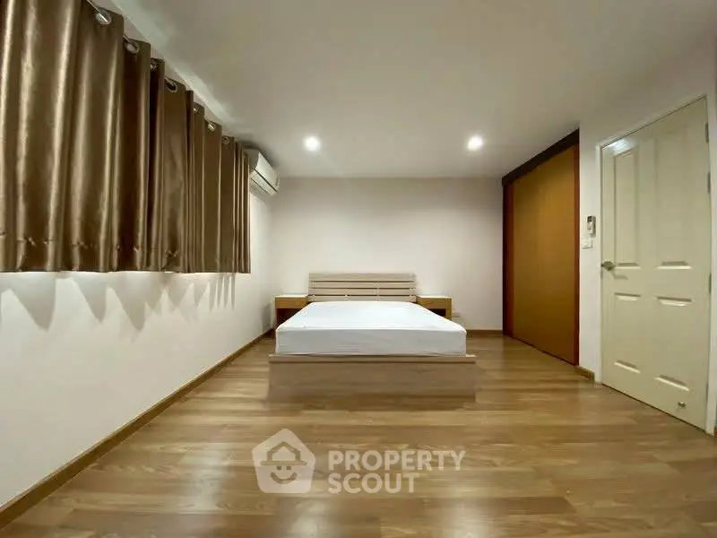 Spacious bedroom with wooden flooring and modern minimalist design