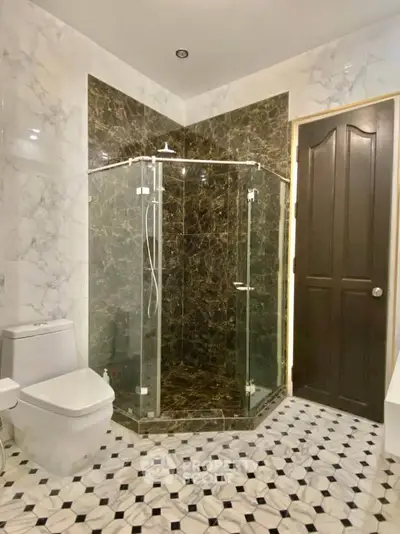 Luxurious bathroom with elegant marble tiles and modern glass shower enclosure.