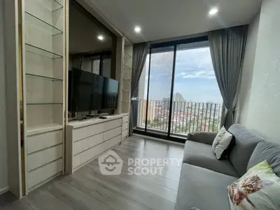 Modern living room with large window and city view, featuring sleek furniture and cozy decor.