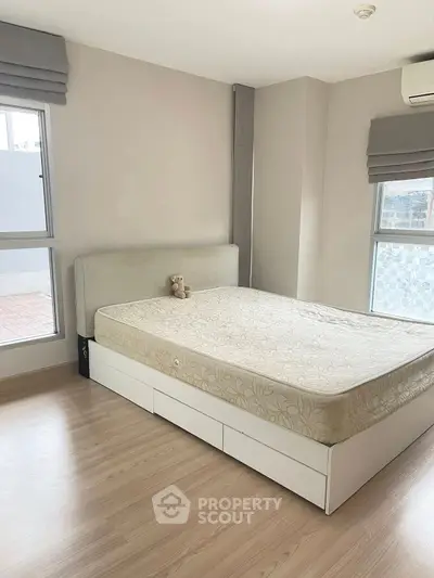 Spacious bedroom with large windows and modern decor, perfect for relaxation.