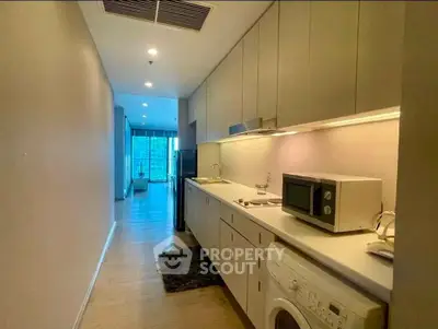 Modern kitchen with sleek cabinetry, washing machine, and microwave in a stylish apartment.
