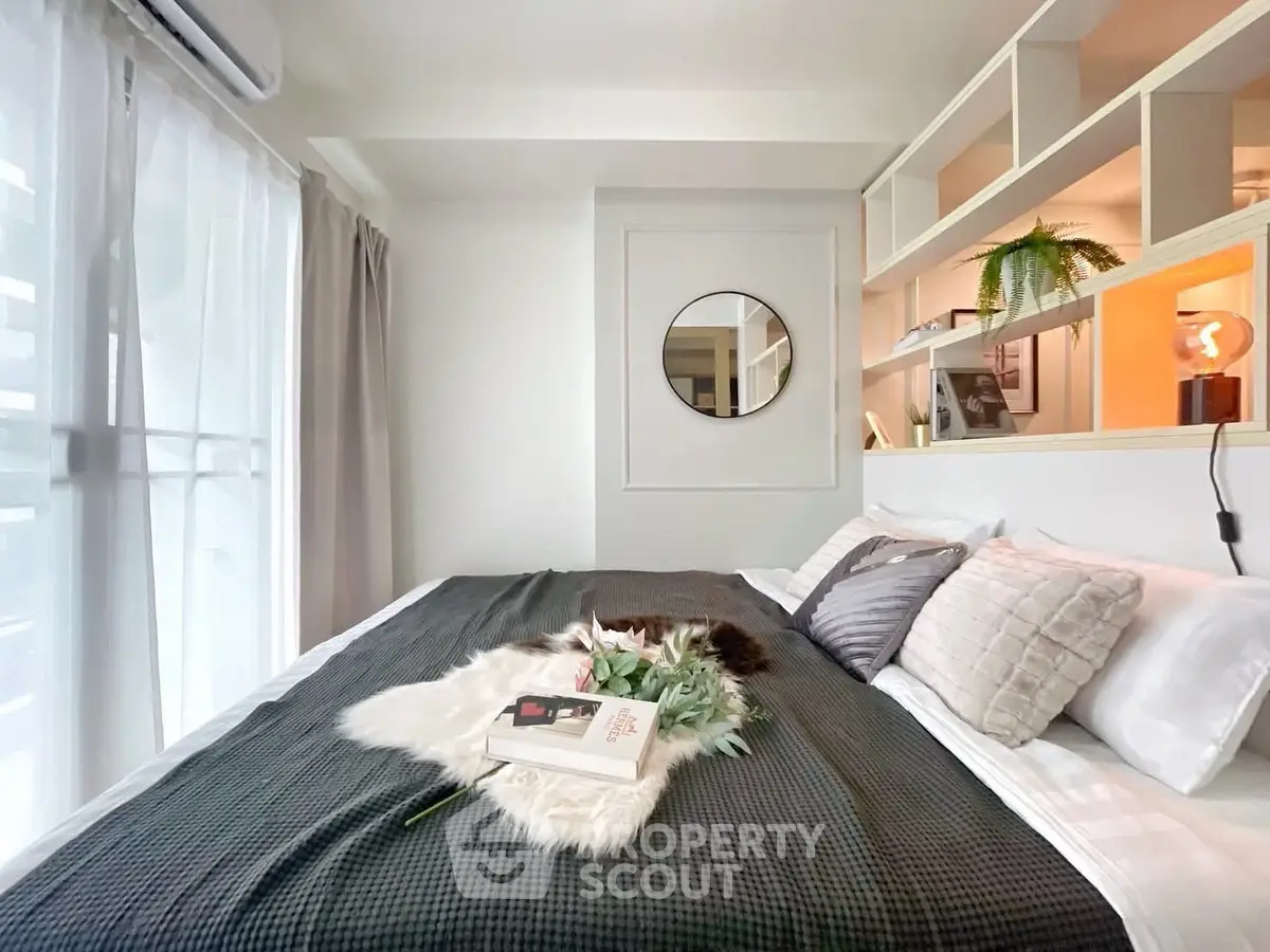 Stylish bedroom with modern decor and natural light, featuring cozy bedding and elegant shelving.