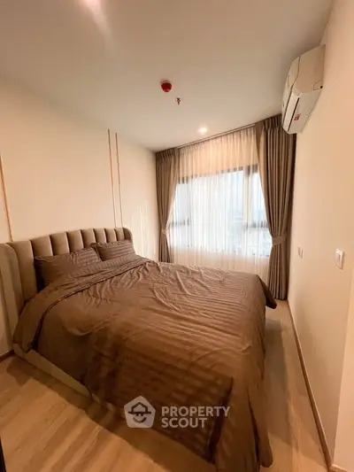 Modern bedroom with large window and stylish curtains in a cozy apartment.