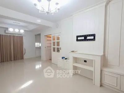 Spacious modern living room with elegant chandelier and built-in storage, perfect for stylish living.