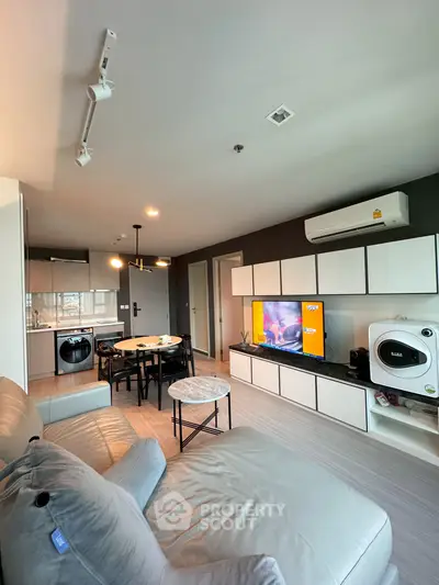Modern living room with open kitchen, stylish decor, and cozy seating area.