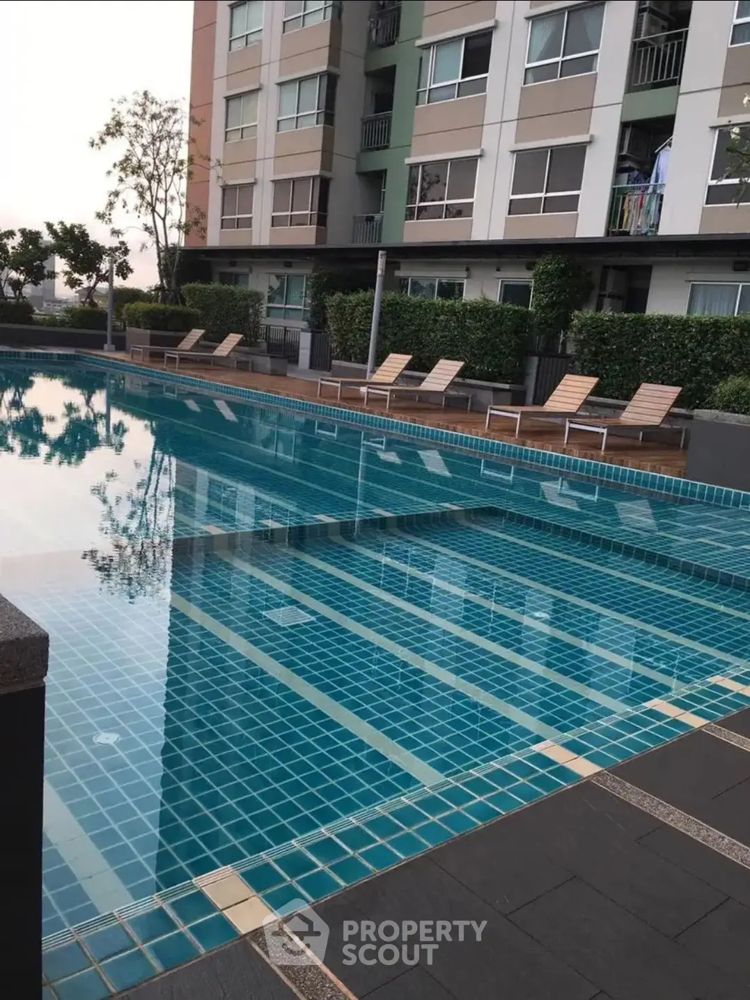 Luxurious condominium pool area with modern design and sun loungers.