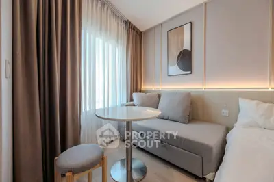 Modern living room with cozy sofa, stylish decor, and natural light from large window.