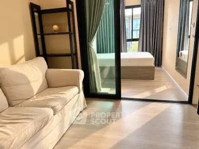 Modern apartment with cozy living room and bedroom separated by glass doors, featuring natural light.