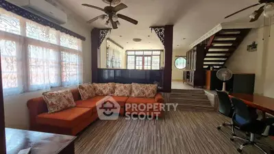 Spacious living room with orange sectional sofa and elegant wooden staircase