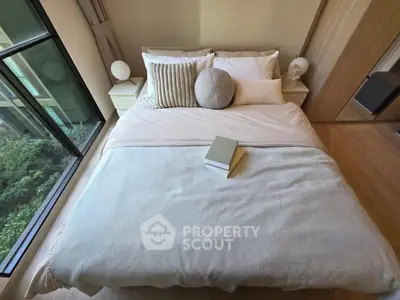 Cozy bedroom with large window and stylish decor, perfect for relaxation and comfort.